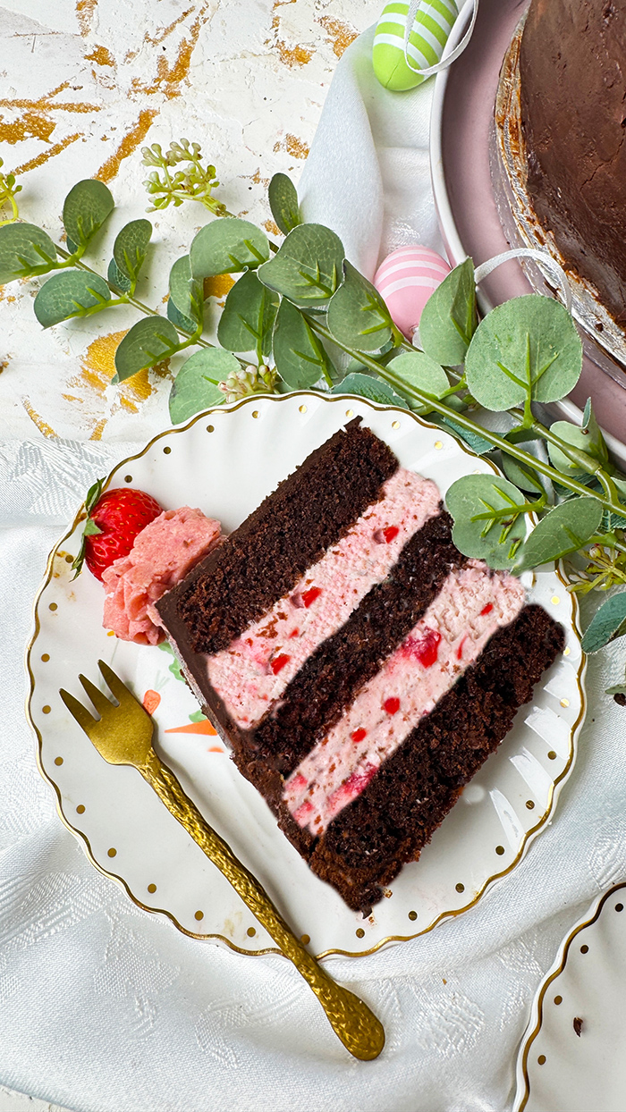Erdbeer-Schokoladen-Torte mit Schokoglasur, Erdbeercreme und Deko, ein Stück ist angeschnitten und liegt auf einem Teller.