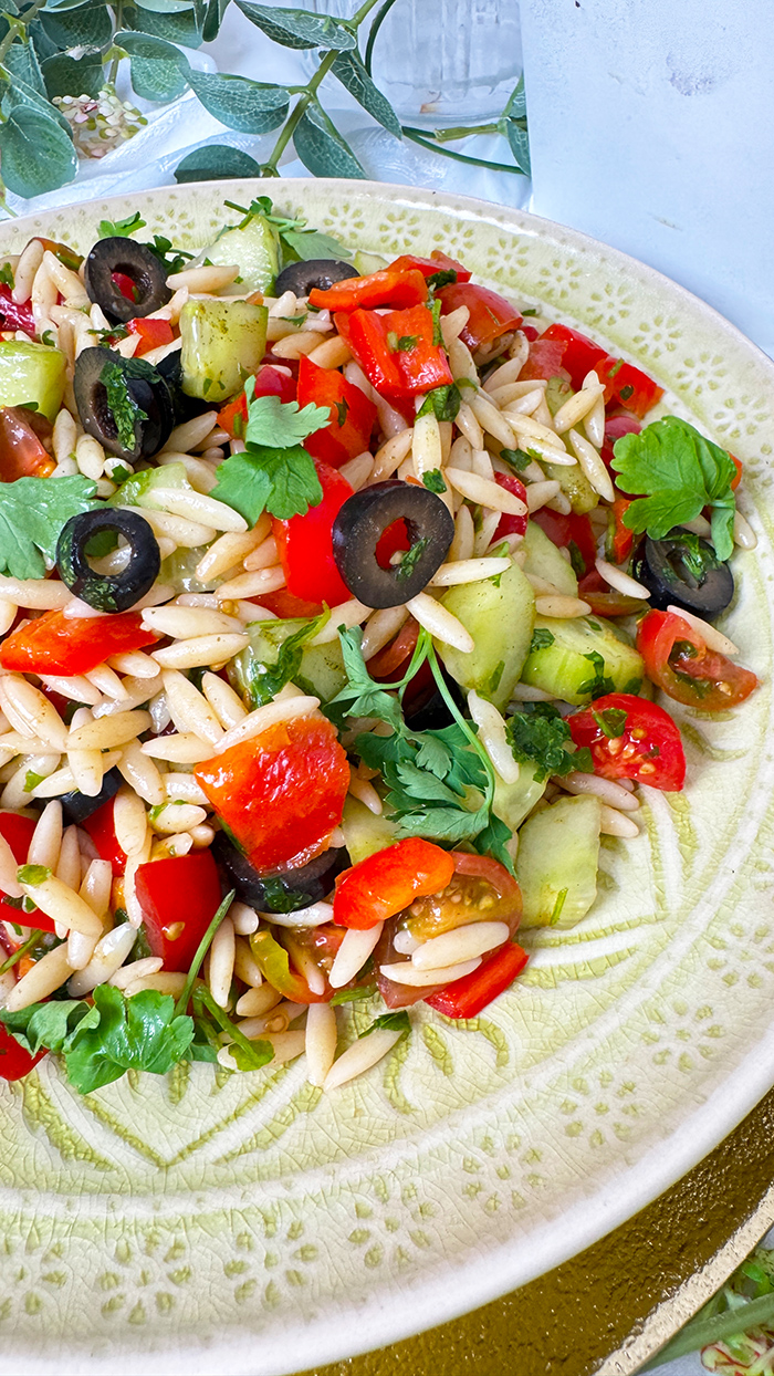 Griechischer Orzo-Salat auf einen Teller angerichtet