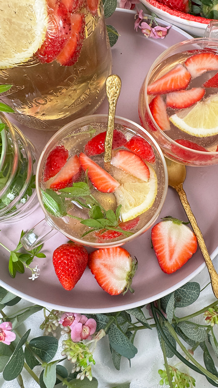 Selbstgemachte Maibowle mit Weißwein, Waldmeister und Sekt, dekoriert mit Zitronenscheiben