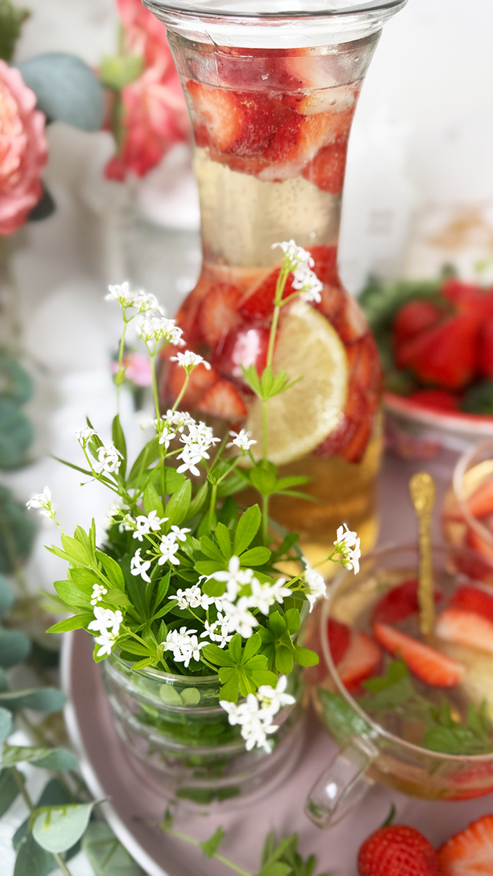Selbstgemachte Maibowle mit Weißwein, Waldmeister und Sekt, dekoriert mit Zitronenscheiben