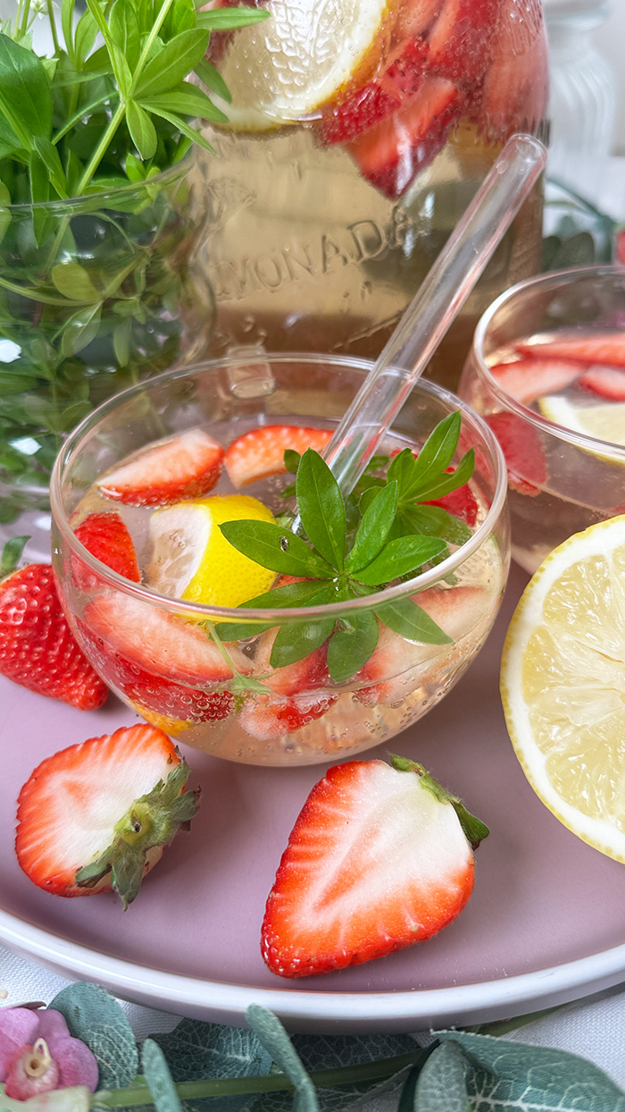 Selbstgemachte Maibowle mit Weißwein, Waldmeister und Sekt, dekoriert mit Zitronenscheiben