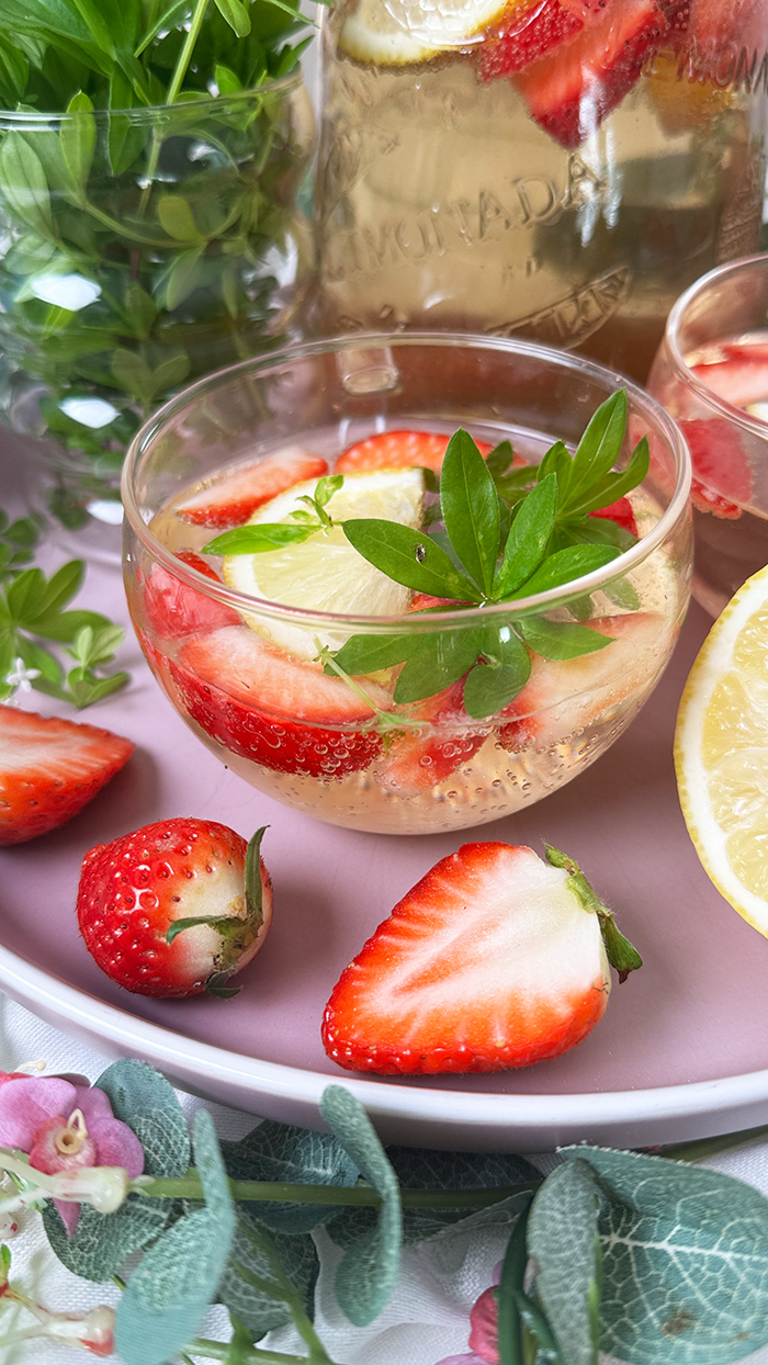 Selbstgemachte Maibowle mit Weißwein, Waldmeister und Sekt, dekoriert mit Zitronenscheiben