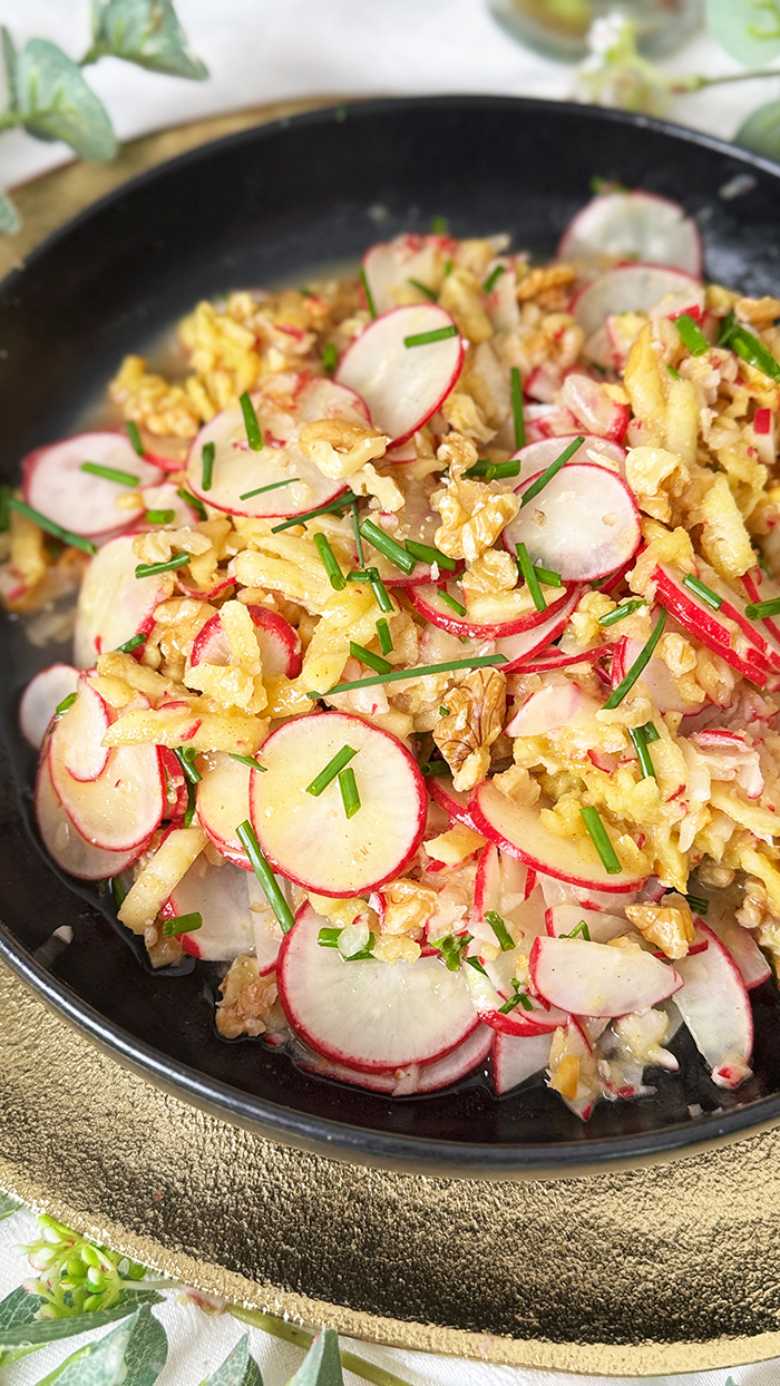 Radieschensalat mit Apfel und Walnüssen auf einen schwarzen Teller, Radieschensalat mit Apfel Rezept