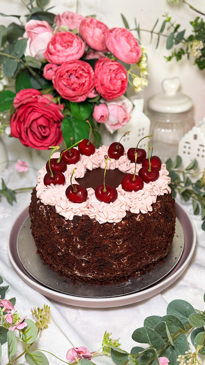 Schoko-Kirsch-Torte auf einen gedeckten Tisch mit Blumen