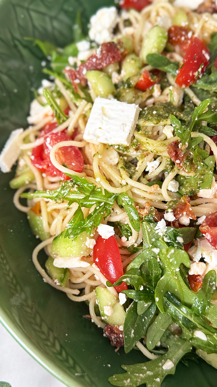 Leichter und aromatischer Spaghettisalat mit cremigem Feta, würzigem Pesto, frischen Tomaten und Rucola in einer Schüssel
