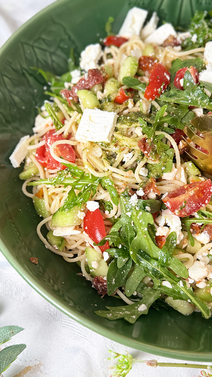 Leichter und aromatischer Spaghettisalat mit cremigem Feta, würzigem Pesto, frischen Tomaten und Rucola in einer Schüssel