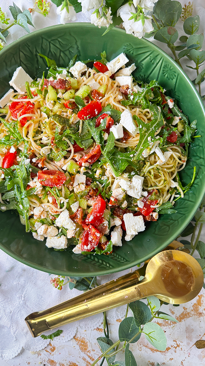Leichter und aromatischer Spaghettisalat mit cremigem Feta, würzigem Pesto, frischen Tomaten und Rucola in einer Schüssel