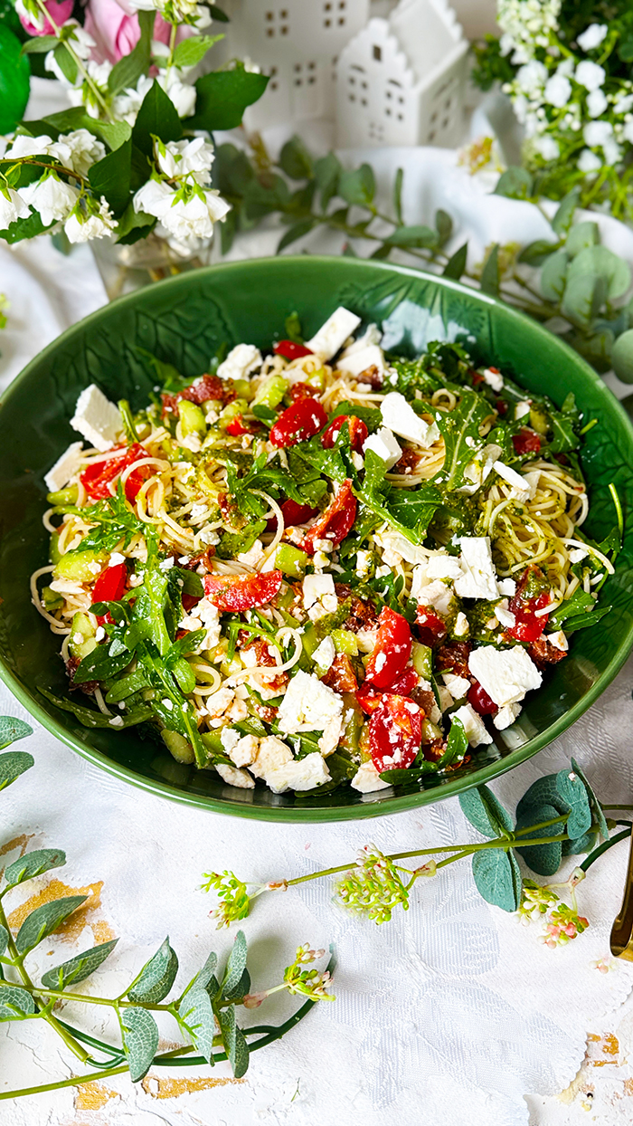 Leichter und aromatischer Spaghettisalat mit cremigem Feta, würzigem Pesto, frischen Tomaten und Rucola in einer Schüssel