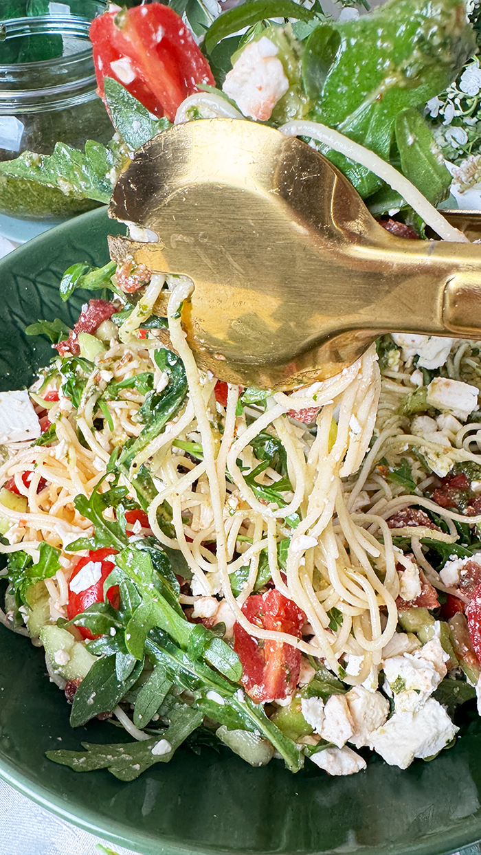 Leichter und aromatischer Spaghettisalat mit cremigem Feta, würzigem Pesto, frischen Tomaten und Rucola in einer Schüssel