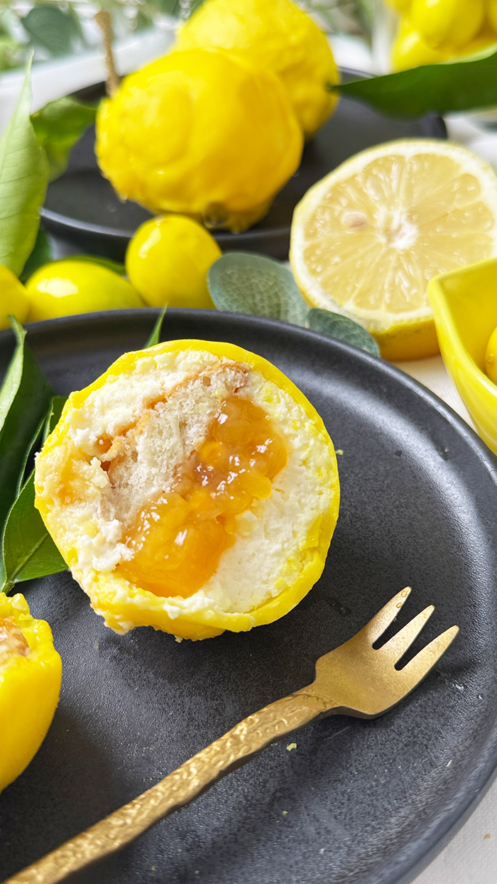 Cedric Grolet Zitronen aufgeschnitten mit Lemon Curd, Mascarponecreme und Plätzchenboden, angerichtet mit frischen Zitronenblättern.