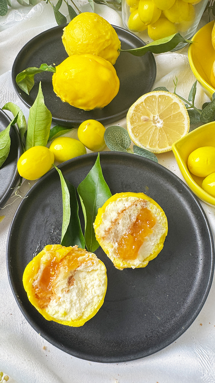 Cedric Grolet Zitronen aufgeschnitten mit Lemon Curd, Mascarponecreme und Plätzchenboden, angerichtet mit frischen Zitronenblättern.