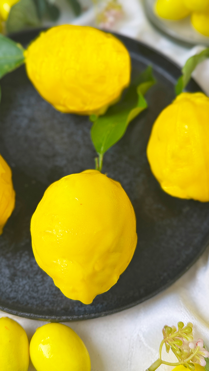 Cedric Grolet Zitronen mit Lemon Curd, Mascarponecreme und Plätzchenboden, angerichtet mit frischen Zitronenblättern.