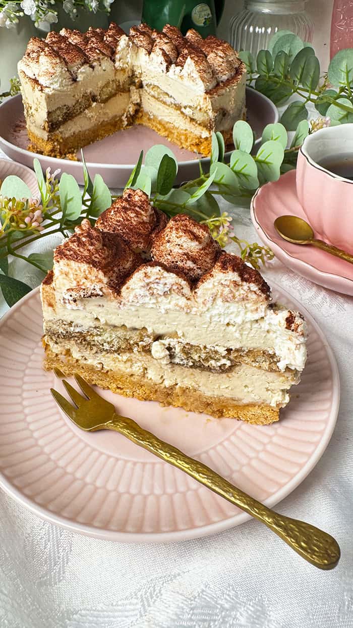 Einfache Tiramisu-Torte ohne Backen: So cremig und 100% kaffeehaft! 2 Tiramisu-Torte ohne Backen mit Mascarponecreme und Kakaopulver, umgeben von Blumen.