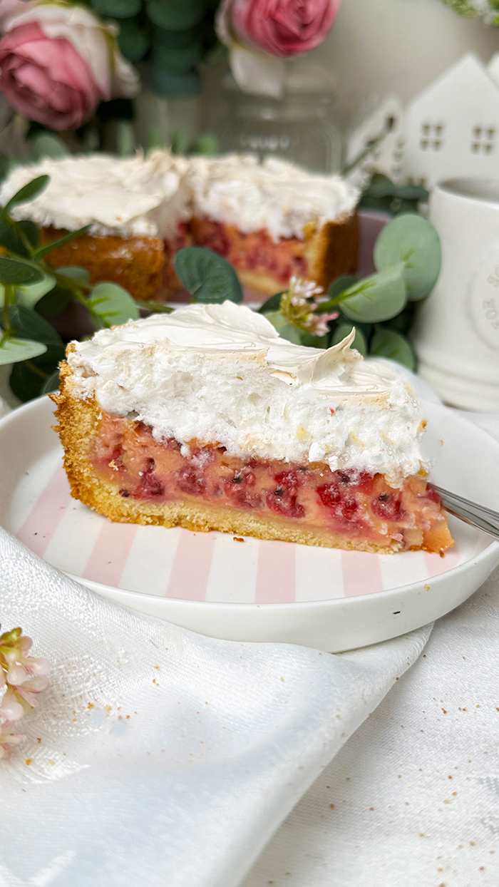 Johannisbeerkuchen Stück mit Baiser auf einer Kuchenplatte serviert