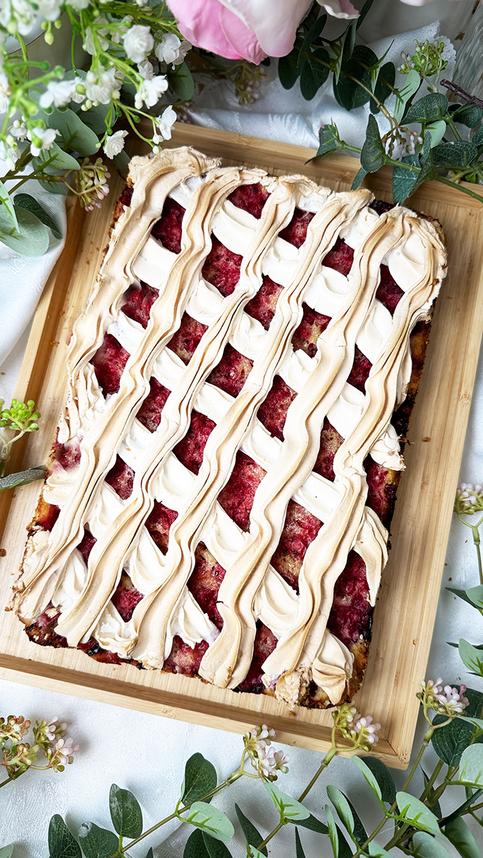 Johannisbeerkuchen mit Baiser vom Blech mit frischen Beeren und Kaffee serviert.