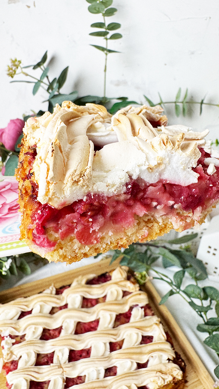 Johannisbeerkuchen mit Baiser vom Blech, in Stücke geschnitten, mit frischen Beeren und Kaffee serviert.