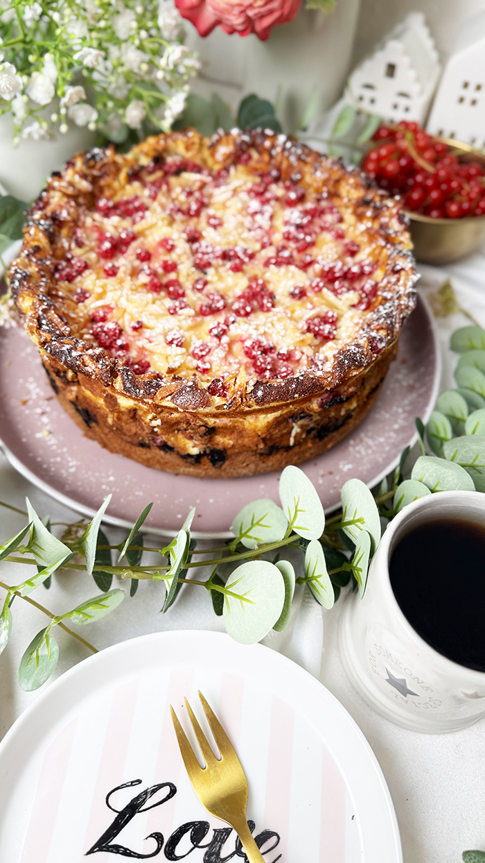 Ein Johannisbeerkuchen mit Mascarponecreme und goldbraunem Mandel-Crunch auf einem Teller, ein Kuchen mit Mandeln und Johannisbeeren