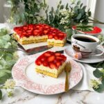 Saftiger Erdbeerkuchen mit Schmand vom Blech, belegt mit frischen Erdbeeren und Tortenguss, serviert auf einem Teller neben einer Tasse Kaffee.