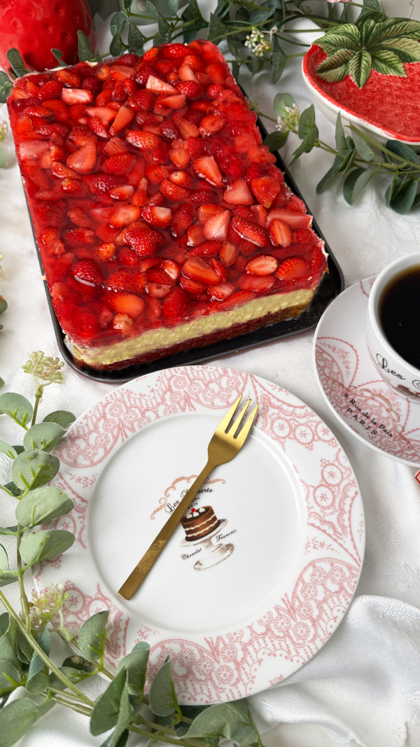 Omas cremiger Erdbeerkuchen mit Schmand vom Blech: einfach unwiderstehlich! 1 Saftiger Erdbeerkuchen mit Schmand vom Blech, belegt mit frischen Erdbeeren und Tortenguss, serviert auf einem Teller neben einer Tasse Kaffee.