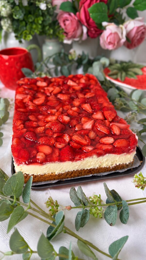 Omas cremiger Erdbeerkuchen mit Schmand vom Blech: einfach unwiderstehlich! 2 Saftiger Erdbeerkuchen mit Schmand vom Blech, belegt mit frischen Erdbeeren und Tortenguss, serviert auf einem Teller neben einer Tasse Kaffee.
