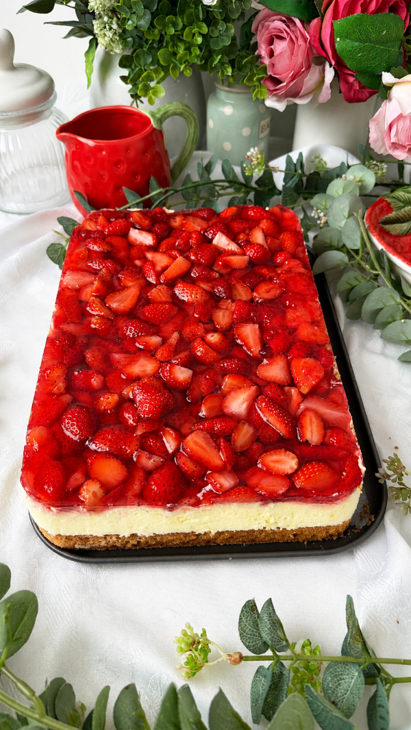 Omas cremiger Erdbeerkuchen mit Schmand vom Blech: einfach unwiderstehlich! 6 Saftiger Erdbeerkuchen mit Schmand vom Blech, belegt mit frischen Erdbeeren und Tortenguss, serviert auf einem Teller neben einer Tasse Kaffee.