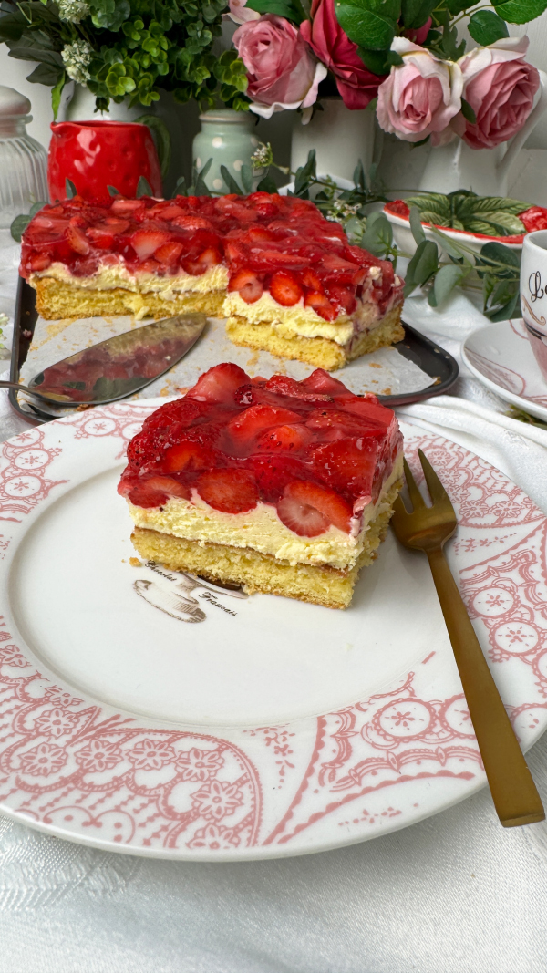 Omas cremiger Erdbeerkuchen mit Schmand vom Blech: einfach unwiderstehlich! 4 Saftiger Erdbeerkuchen mit Schmand vom Blech, belegt mit frischen Erdbeeren und Tortenguss, serviert auf einem Teller neben einer Tasse Kaffee.