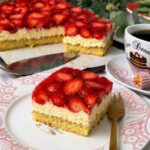 Saftiger Erdbeerkuchen mit Schmand vom Blech, belegt mit frischen Erdbeeren und Tortenguss, serviert auf einem Teller neben einer Tasse Kaffee.