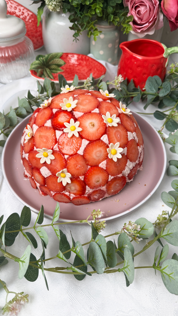 Erdbeer-Kuppeltorte – cremig, fruchtig & unwiderstehlich 6 Erdbeer-Kuppeltorte mit zartem Erdbeermuster außen auf einer Tortenplatte, dekoriert mit Dekorblüten