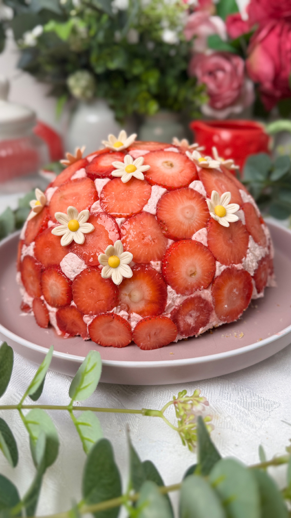 Erdbeer-Kuppeltorte – cremig, fruchtig & unwiderstehlich 8 Erdbeer-Kuppeltorte mit zartem Erdbeermuster außen auf einer Tortenplatte, dekoriert mit Dekorblüten