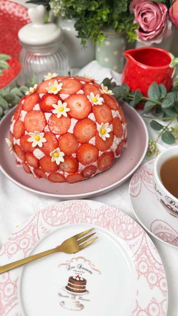 Erdbeer-Kuppeltorte – cremig, fruchtig & unwiderstehlich 7 Erdbeer-Kuppeltorte mit zartem Erdbeermuster außen auf einer Tortenplatte, dekoriert mit Dekorblüten