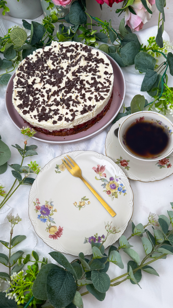 Stachelbeertorte mit Mascarpone, einfach fruchtig und cremig 7 Eine selbstgemachte Stachelbeertorte mit Mascarpone-Creme und Schokostreuseln auf einer rosa Etagere, im Hintergrund dekorative Blumen.