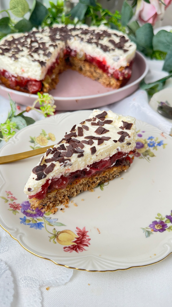 Stachelbeertorte mit Mascarpone, einfach fruchtig und cremig 4 Eine selbstgemachte Stachelbeertorte mit Mascarpone-Creme und Schokostreuseln auf einer rosa Etagere, im Hintergrund dekorative Blumen.