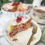 Johannisbeerkuchen mit Schmand auf einem Teller, saftiger Rührkuchen mit roten Johannisbeeren und cremigem Schmand Swirl, mit Puder