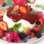 oghurtbombe mit frischen Beeren, Beerensauce und Puderzucker auf einer Tortenplatte