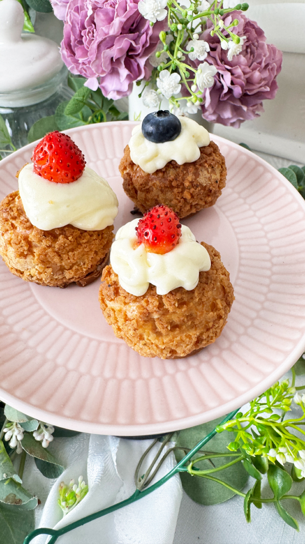 Choux au Craquelin mit Vanillecreme, knusprig & cremig 4 Drei Choux au Craquelin mit Vanillecreme und frischen Erdbeeren und Heidelbeeren auf einem Teller