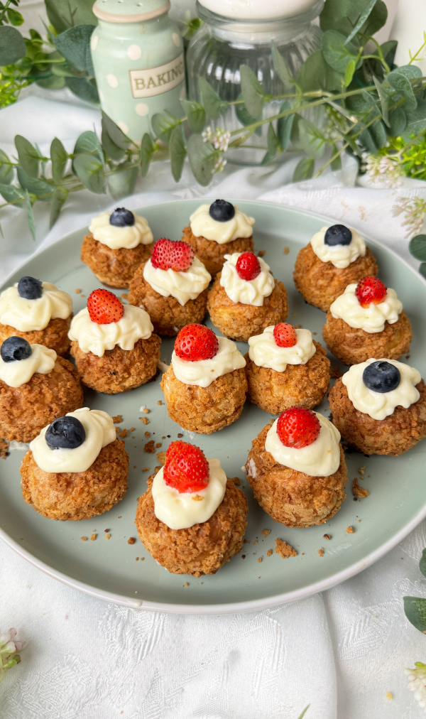 Choux au Craquelin mit Vanillecreme, knusprig & cremig 1 Viele Choux au Craquelin mit Vanillecreme und frischen Erdbeeren und Heidelbeeren auf einem Teller