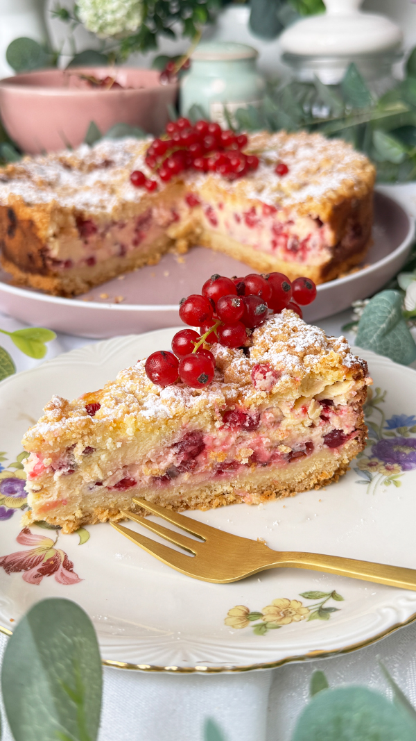Johannisbeerkuchen mit Quark und Streuseln, cremig & fruchtig 7 Johannisbeerkuchen mit Quark und Streuseln, angeschnitten mit einem Kuchenstück und frischen roten Johannisbeeren