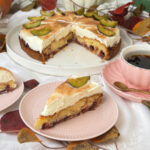 Zwetschgen-Schmand-Kuchen, saftig & cremig 6 Angeschnittener Zwetschgen-Schmand-Kuchen mit saftigem Zwetschgenbelag und cremiger Schmandhaube, dazu ein Kuchenstück auf einem rosa Teller.