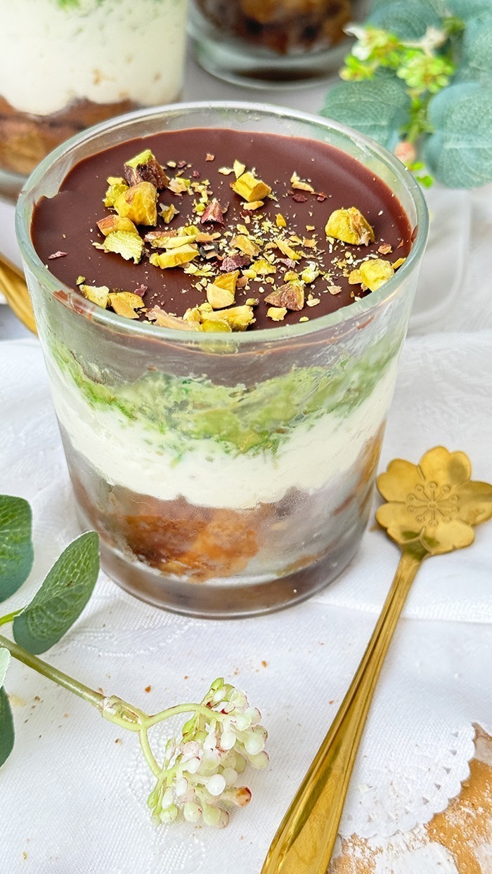 Ein kunstvoll Dubai Schokoladen Tiramisu geschichtetes Tiramisu im Glas, bestehend aus Schokoladenbiskuit, cremiger Mascarpone, Pistaziencreme und einer Schokoladenglasur, garniert mit gehackten Pistazien.
