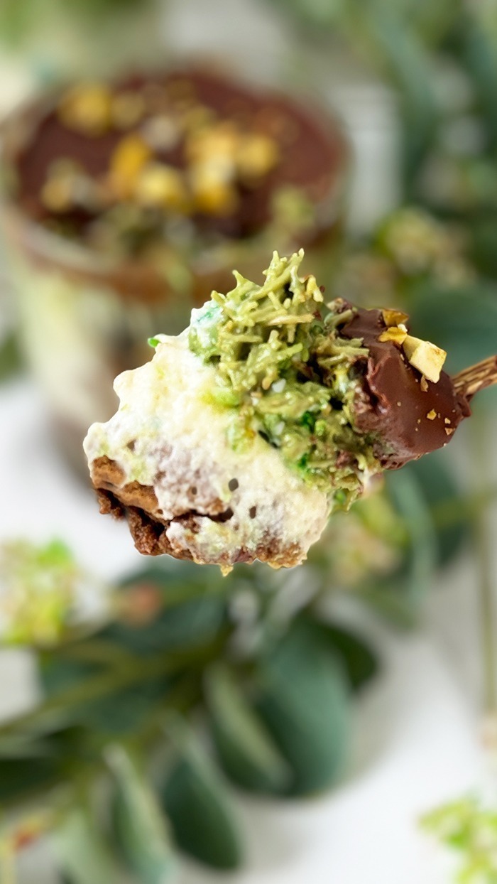 Ein kunstvoll Dubai Schokoladen Tiramisu geschichtetes Tiramisu im Glas, bestehend aus Schokoladenbiskuit, cremiger Mascarpone, Pistaziencreme und einer Schokoladenglasur, garniert mit gehackten Pistazien.