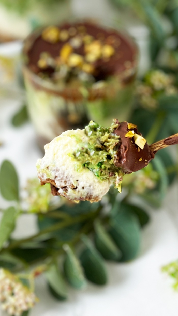 Ein kunstvoll Dubai Schokoladen Tiramisu geschichtetes Tiramisu im Glas, bestehend aus Schokoladenbiskuit, cremiger Mascarpone, Pistaziencreme und einer Schokoladenglasur, garniert mit gehackten Pistazien.