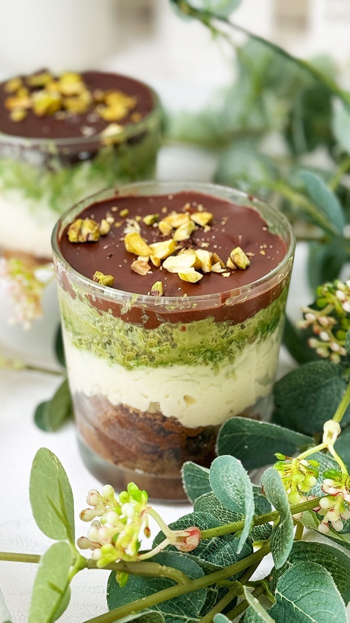 Ein kunstvoll Dubai Schokoladen Tiramisu geschichtetes Tiramisu im Glas, bestehend aus Schokoladenbiskuit, cremiger Mascarpone, Pistaziencreme und einer Schokoladenglasur, garniert mit gehackten Pistazien.