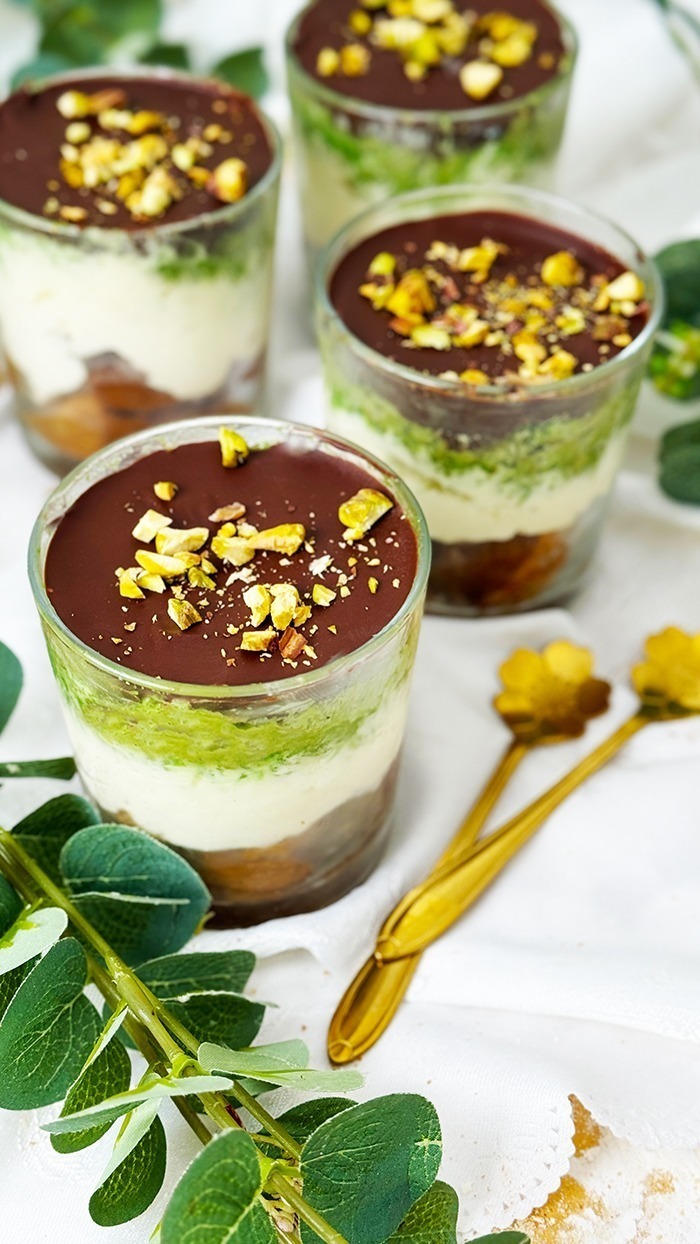 Ein kunstvoll Dubai Schokoladen Tiramisu geschichtetes Tiramisu im Glas, bestehend aus Schokoladenbiskuit, cremiger Mascarpone, Pistaziencreme und einer Schokoladenglasur, garniert mit gehackten Pistazien.