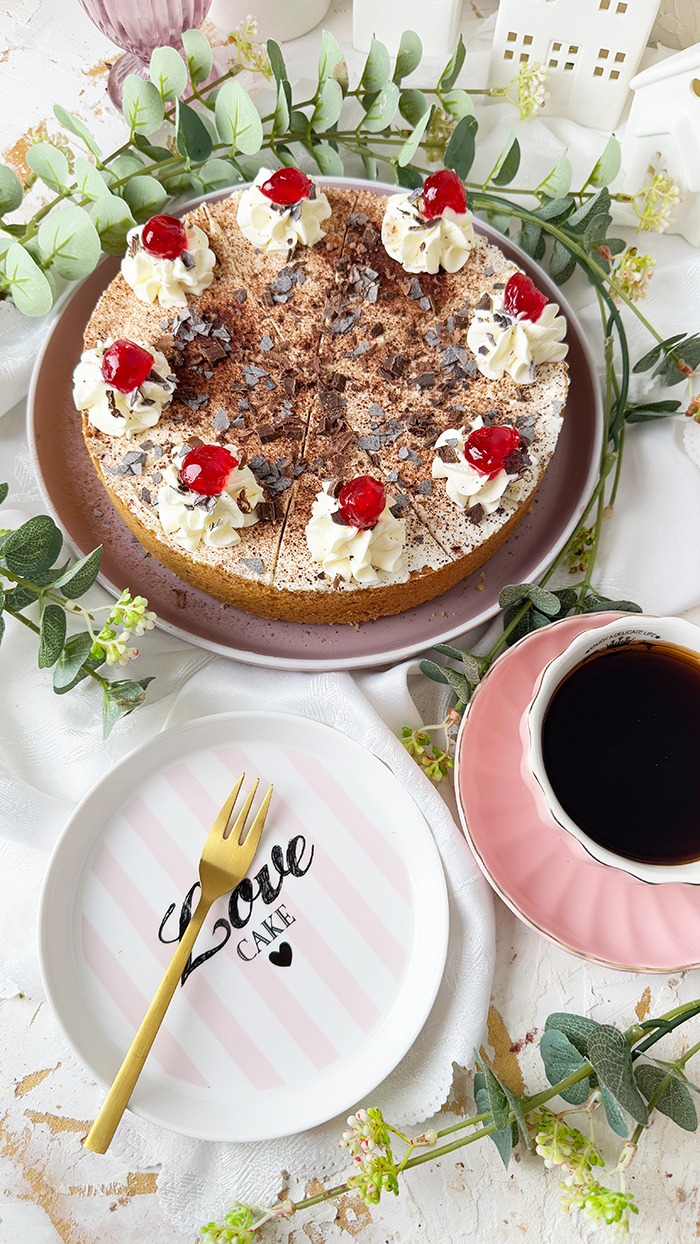 Ein Feuerwehrkuchen mit Schlagsahne und Kirschen obenauf und eine Tasse Kaffee
