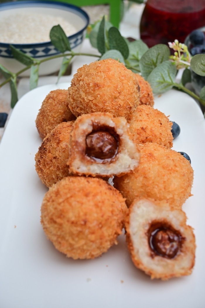 Ebackene milchreisbällchen mit schokoladenkern und beerensoße