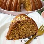 Ein saftiger Nusskuchen im Gugelhupf-Stil mit Haselnussglasur und gehackten Nüssen liegt auf einem dekorativen Teller, während der gesamte Kuchen im Hintergrund präsentiert wird.