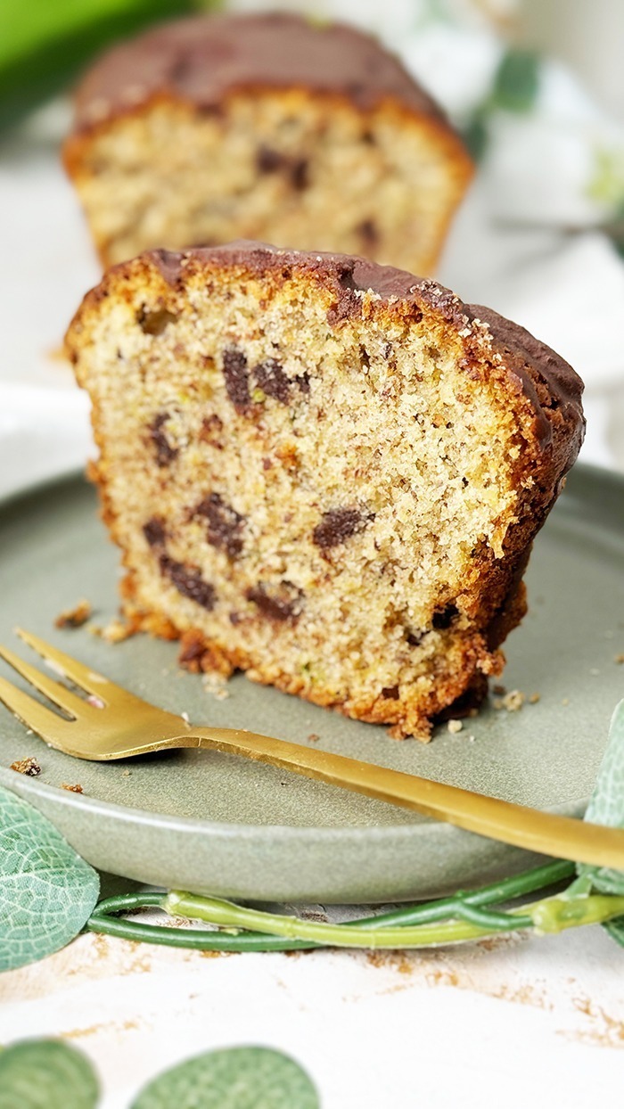 Ein saftiger Zucchinikuchen mit Schokolade, veredelt durch eine glänzende Glasur und Schokostückchen, ideal für gemütliche Kaffeepausen.