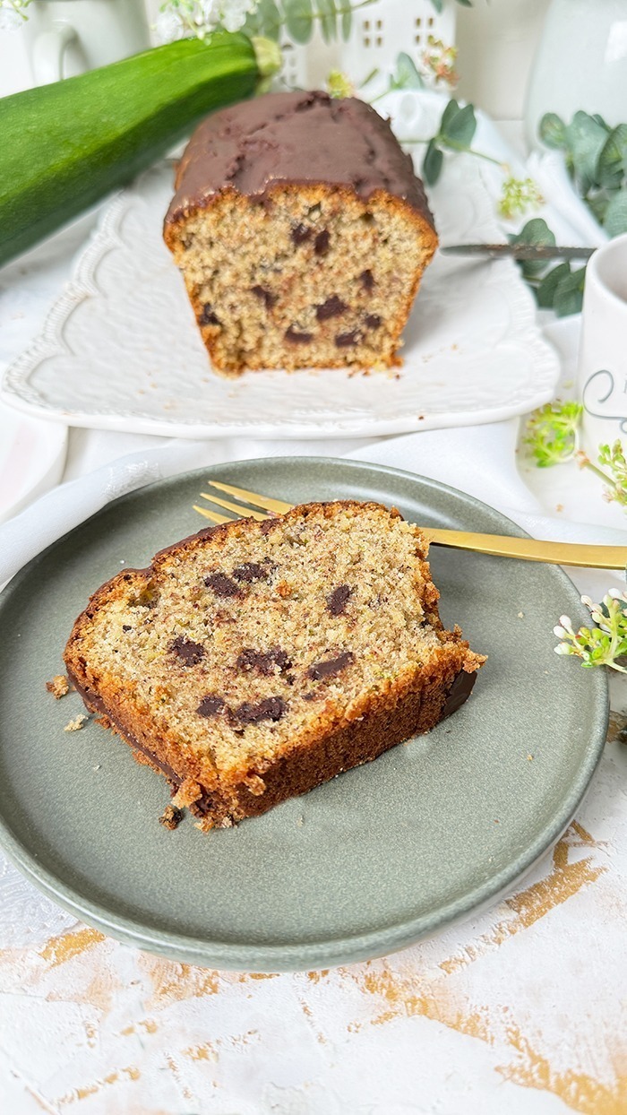 Ein saftiger Zucchinikuchen mit Schokolade, veredelt durch eine glänzende Glasur und Schokostückchen, ideal für gemütliche Kaffeepausen.