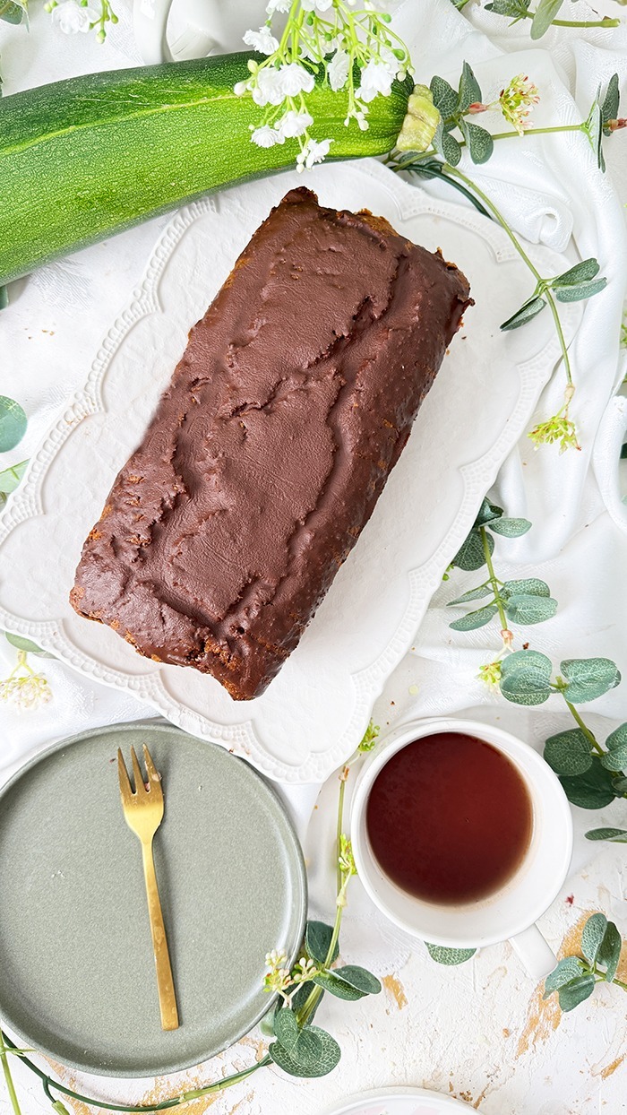 Ein saftiger Zucchinikuchen mit Schokolade, veredelt durch eine glänzende Glasur und Schokostückchen, ideal für gemütliche Kaffeepausen.