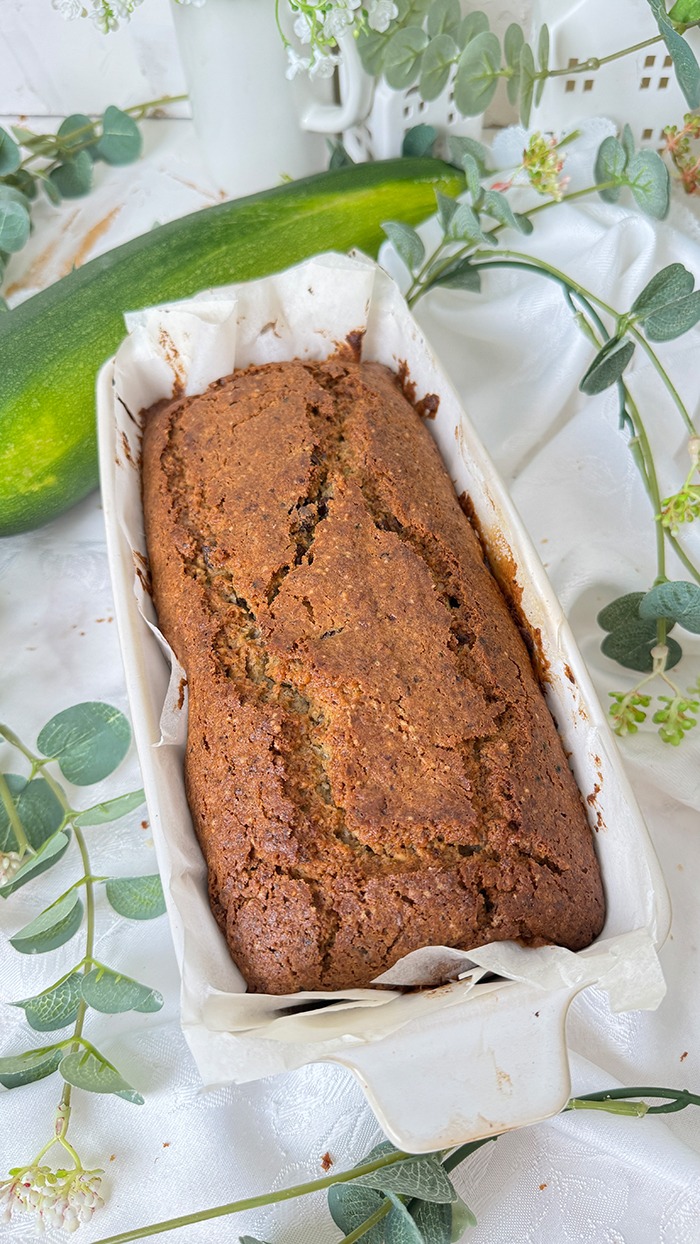 Ein saftiger Zucchinikuchen mit Schokolade, veredelt durch eine glänzende Glasur und Schokostückchen, ideal für gemütliche Kaffeepausen.